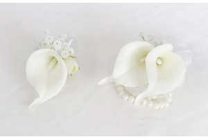 Detail of white calla lily wedding boutonniere and pearl wrist corsage set