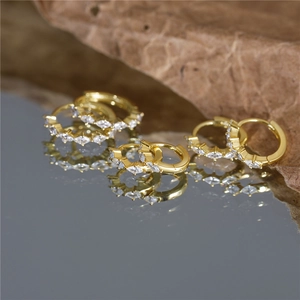 Macro view of gold plated silver hoop earrings with marquise cut sparkling zircons