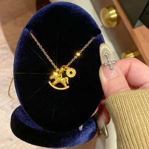 24k gold-plated lucky horse and coin pendant necklace shown on a blue velvet stand