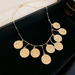 Close-up of vintage gold coin pendants on a chain inside a black velvet jewelry box