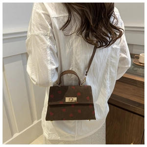 Corduroy crossbody bag with red heart pattern shown on a model in a natural setting