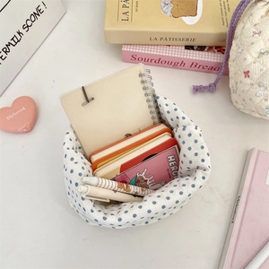 Detailed top view of quilted blue polka dot storage bag with stationery and makeup tools