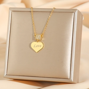 Golden heart pendant necklace with Love engraving and cubic zirconia on a gift box