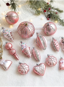 Close-up of pink Christmas ornaments in star and heart shapes on white faux fur background