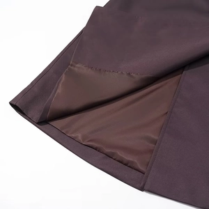Détail macro de l'ourlet d'un manteau violet foncé montrant la doublure intérieure lisse