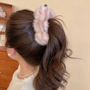 Gros plan sur une pince à cheveux en peluche rose poudré pour une coiffure élégante