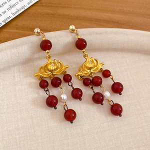 Macro shot of vintage lotus earrings with red agate beads and white pearls on a tray