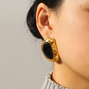 Detail of vintage irregular 18k gold earrings with black resin inlay on model