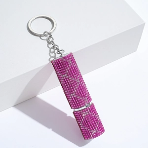 Macro view of portable pink rhinestone encrusted perfume bottle keychain on white background