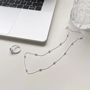Flat lay of minimalist 925 silver beaded necklace and light blue square stone ring