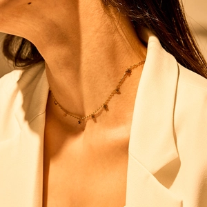 Detailed view of a gold dainty necklace with star pendants worn by a model in warm light