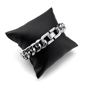 Close-up of silver Cuban link bracelet on a black leather cushion with a sleek buckle