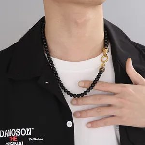 Macro detail of men's black beaded necklace with a golden leopard head clasp