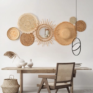 Detailed arrangement of woven seagrass wall plates and sunburst mirror in boho style