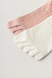 Close-up of non-slip silicone grippers on pink and beige cotton five-toe yoga socks