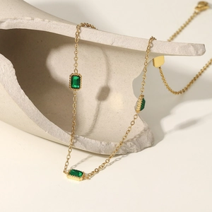 Gros plan d'un collier en or avec trois zircons verts rectangulaires de style vintage