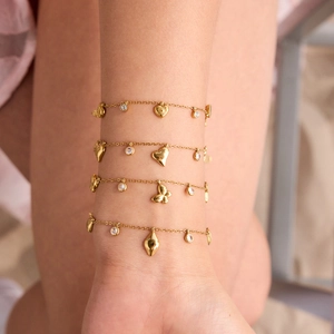 Close-up of 18K gold plated butterfly and heart zircon layered bracelets on wrist