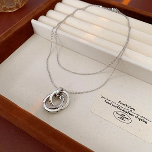 Detail view of silver interlocking triple ring pendant necklace in a display box