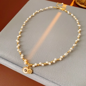 Detailed shot of pearl and gold bead necklace with enamel evil eye and starburst pendants