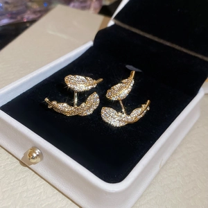 Macro detail of gold-plated feather earrings with micro-pave zircons in a jewelry box