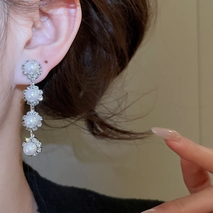 Detail of silver drop earrings with white pearls and sparkling crystal rhinestones