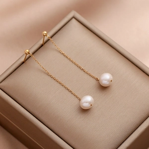 Elegant natural pearl drop earrings with long gold chains on champagne jewelry box