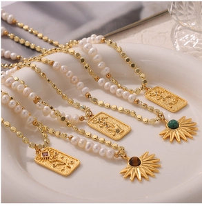 Close-up of golden necklaces with freshwater pearls and tiger eye stone pendants in a tray