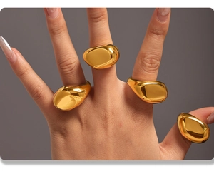 Close-up of four chunky gold irregular rings on hand featuring smooth metallic textures