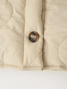 Detailed macro view of dark tortoise shell buttons on a beige diamond quilted jacket