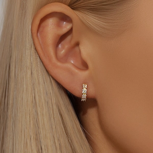 Close-up of a gold s925 silver huggie hoop earring with heart design and tiny diamonds