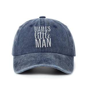 Detailed view of white embroidered MAMA'S little MAN text on navy washed denim baseball cap
