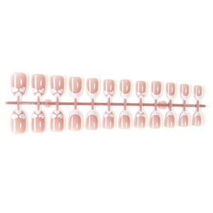 French tip press-on nails with white heart patterns and glitter on pink base