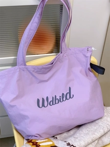 Close-up of light purple drawstring canvas tote bag on a yellow chair, detail view