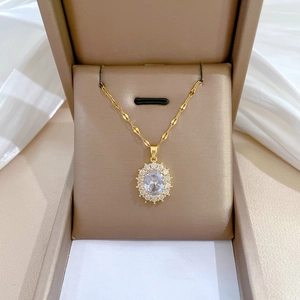 Detail of gold oval halo necklace with sparkling zircon cluster on jewelry box