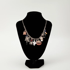 Gold Halloween charm necklace with pumpkin, ghost and spider charms on black neck display