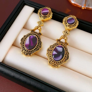 Detailed view of vintage gold-tone oval earrings with purple stones in a gift box