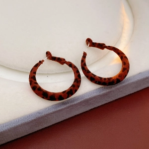 Gros plan de boucles d'oreilles rondes en velours léopard sur un support à bijoux