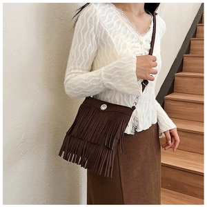 Brown fringe crossbody bag with suede-like texture and metal buckle shown on a model
