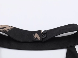Detail of black halter neck closure with two buttons and abstract printed pattern