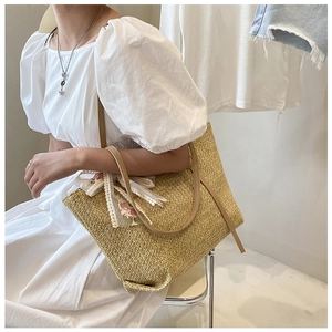 Macro view of woven straw tote bag featuring delicate floral lace ribbon and leather strap