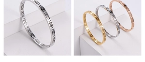 Detailed view of hollow Greek key pattern bracelets in steel, gold, and rose gold finishes