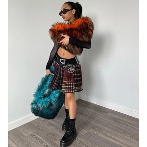 Street style shot of luxury orange faux fur stole and blue plush handbag with plaid skirt