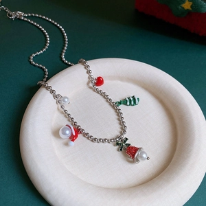 Detailed view of silver bead necklace with Christmas charms on a ceramic tray