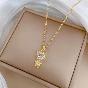 Close-up of golden bear pendant with sparkling crystals on a white silk background