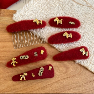 Detailed macro view of red plush hair clips with gold alloy horse and coin decorations