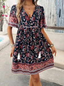 Detailed view of dark blue floral dress with V-neckline, buttons and white tassel accents