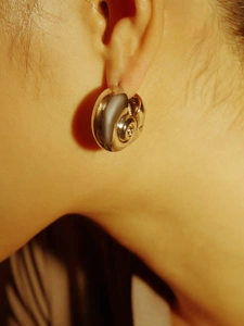 Close-up of a silver snail shell spiral earring on a model showing smooth mirror finish