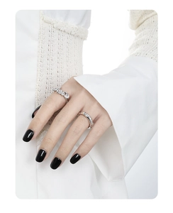 Detail of silver wavy rings with crystals shown on hand with black manicure