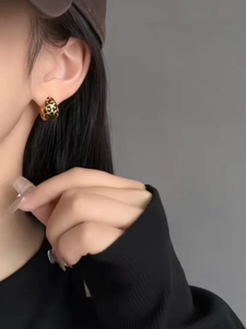 Close-up of a model wearing leopard print geometric gold hoop earrings with black spots