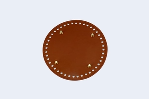 Macro view of 15cm round brown leather bag bottom with golden metal feet and pre-drilled holes